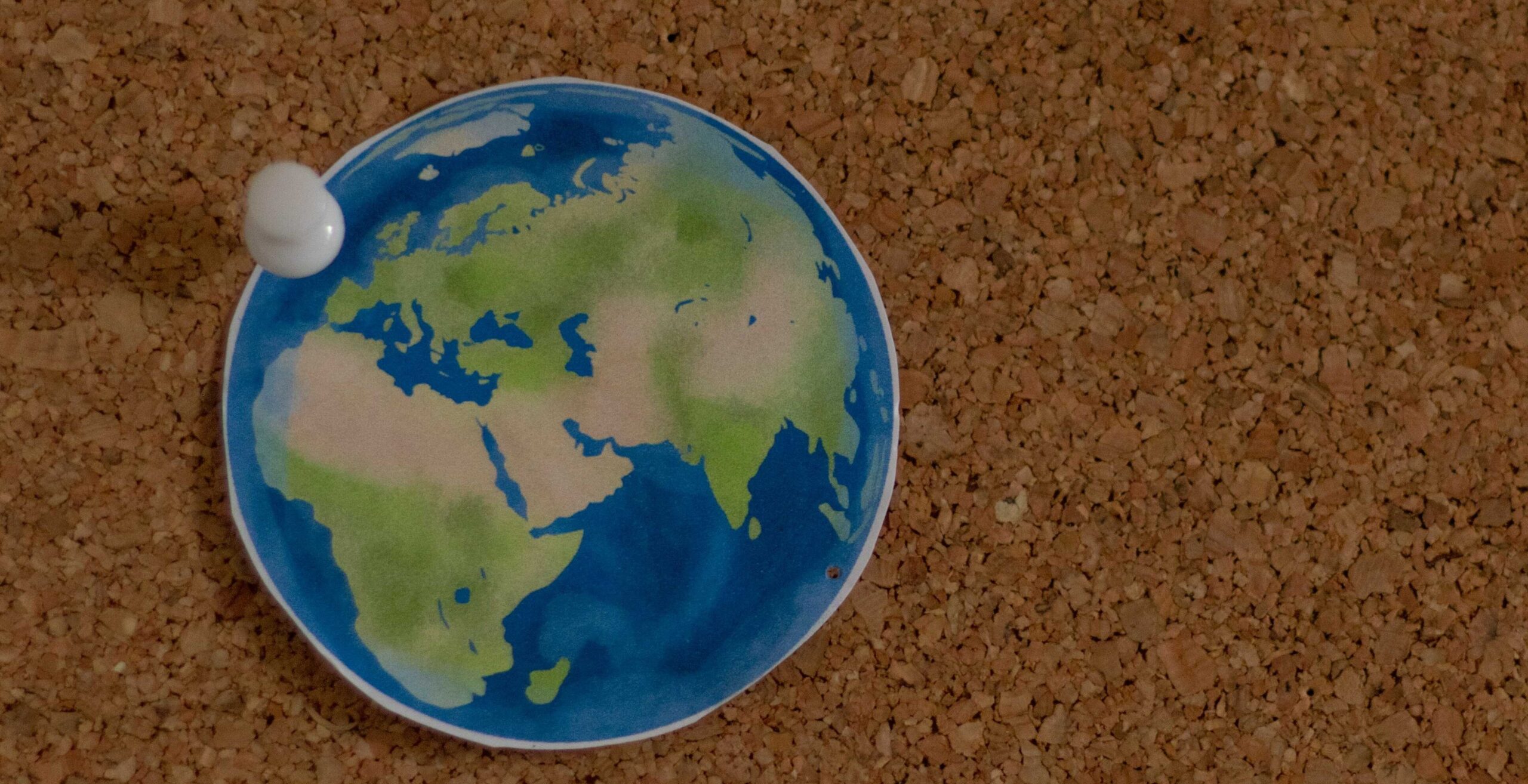 Cut-out shape of the Earth pinned to a corkboard.